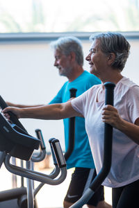 Smiling senior couple exercising at gym
