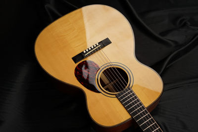 High angle view of acoustic guitar on bed