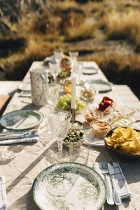 High angle view of snacks with crockery kept of table for outdoor dining at sunny day
