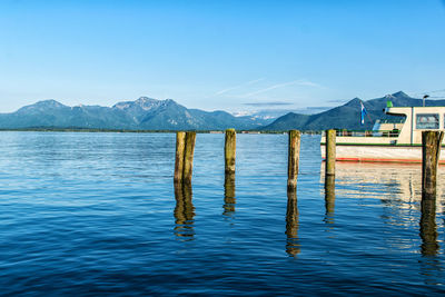 Wooden posts in lake against blue sky