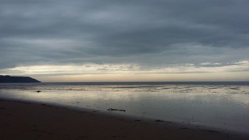 Scenic view of beach against cloudy sky