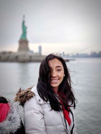 Portrait of smiling woman sitting against statue of liberty