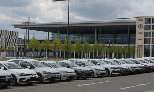 Row of cars on road against cloudy sky