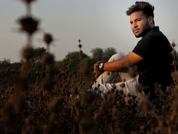 Man looking away while sitting on field