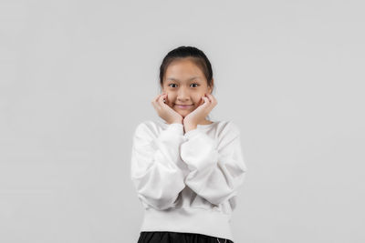 Portrait of smiling girl standing against white background