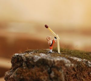 Optical illusion of toy breaking matchstick on rock