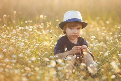 Portrait of boy standing amidst plants on field
