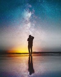 Silhouette man standing in water against sky at night