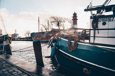 Boats moored at harbor against sky in city