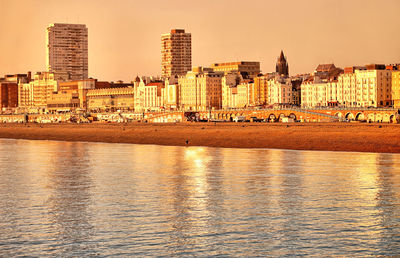 River by buildings against sky during sunset