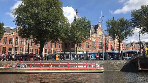 Boats in canal by buildings against sky