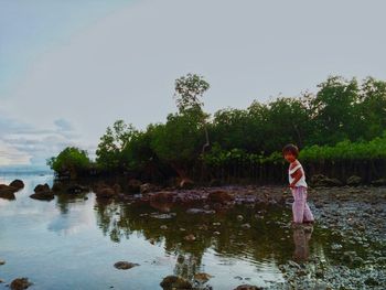 Full length of woman standing by lake against sky