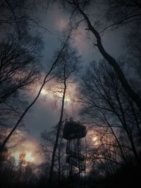 Low angle view of bare trees against cloudy sky