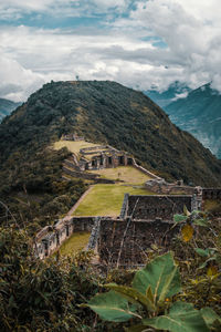 View of old ruins on mountain against cloudy sky