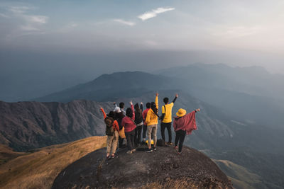 People looking at mountains against sky