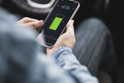 Hands of woman using mobile app to operate electric car