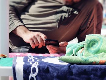 Midsection of man using smart phone at home