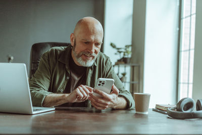 Young woman using mobile phone while sitting on table