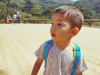 Cute boy looking away while standing on footpath