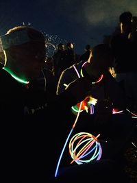 People standing against illuminated sky at night