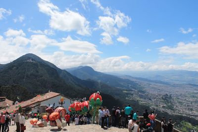 People looking at town by mountains against sky