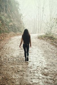 Rear view of woman walking on road
