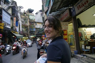 Portrait of woman on street amidst buildings in city