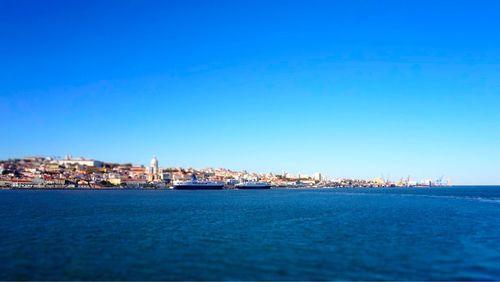 Scenic view of sea by city against clear blue sky