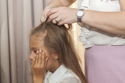 Midsection of mother tying up her daughters hair