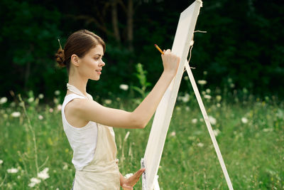 Side view of young woman standing on field