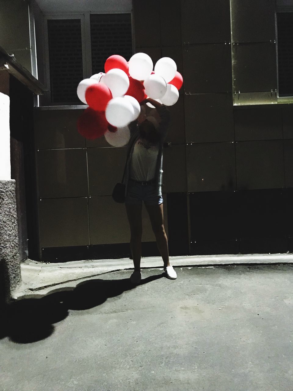 REAR VIEW OF WOMAN HOLDING BALLOONS WITH UMBRELLA