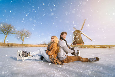 Portrait of young woman sitting on snow covered field