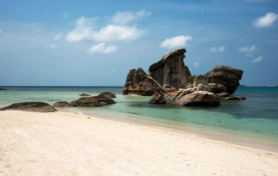 Rock formation on beach against sky