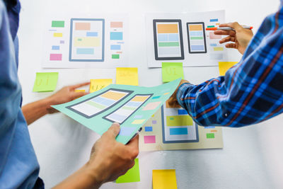 Cropped hand of colleagues brainstorming while holding paper at office