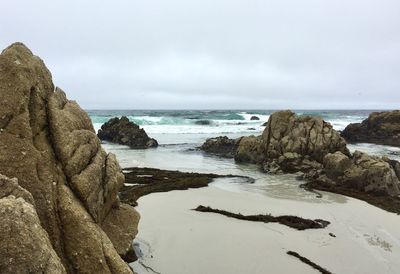Scenic view of rocks on beach against sky
