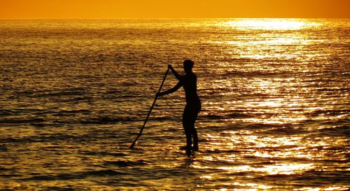 Silhouette of people in sea at sunset