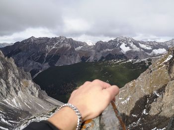 Midsection of person on snowcapped mountains against sky