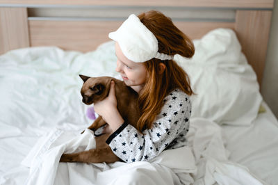 Rear view of woman sleeping on bed at home