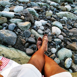 Low section of woman standing on pebbles at beach