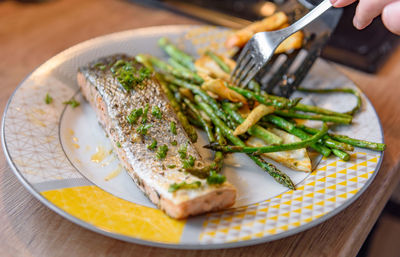 Close-up photo of person preparing grilled salmon with asparagus