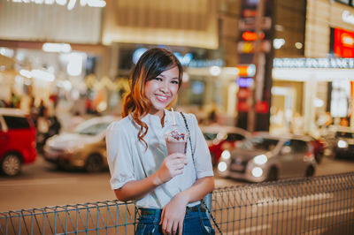 Portrait of a smiling young woman standing in city