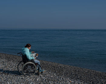 Rear view of man standing by sea against clear sky