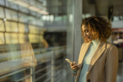 Woman using mobile phone in station