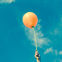 Low angle view of balloons flying against blue sky