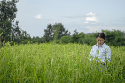 Beautiful woman standing on farm against sky