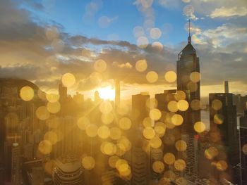 Defocused image of illuminated buildings against sky at sunset