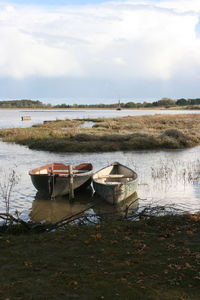 Boats moored on lake against sky