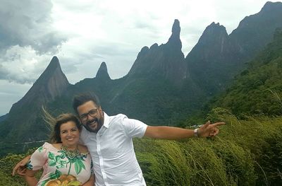 Portrait of a smiling young couple on mountain against sky