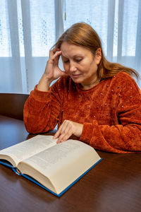 Mature woman reading book at home