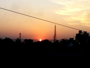 Silhouette of electricity pylon at sunset